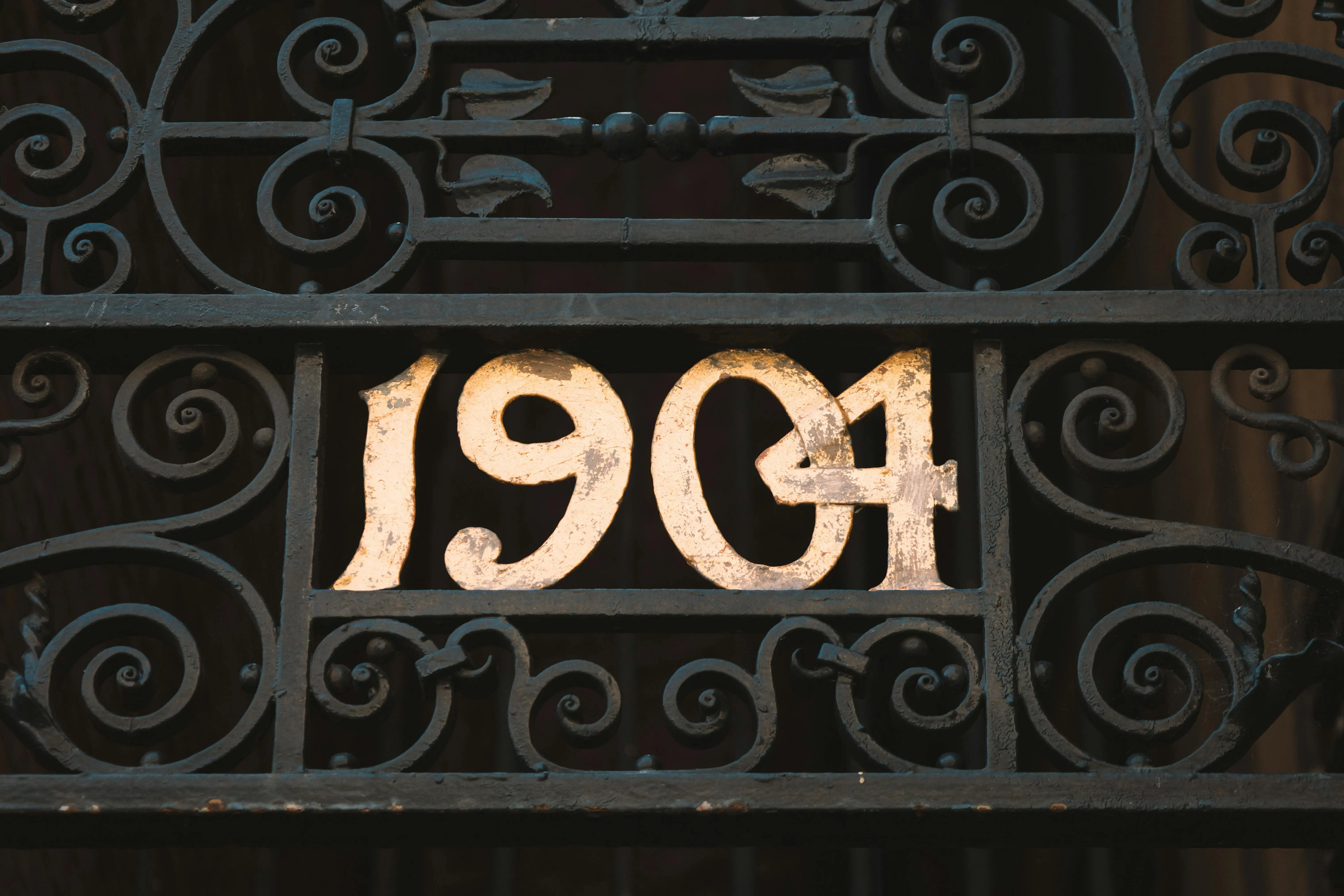 Dekorativ smidestext som lyder 1904