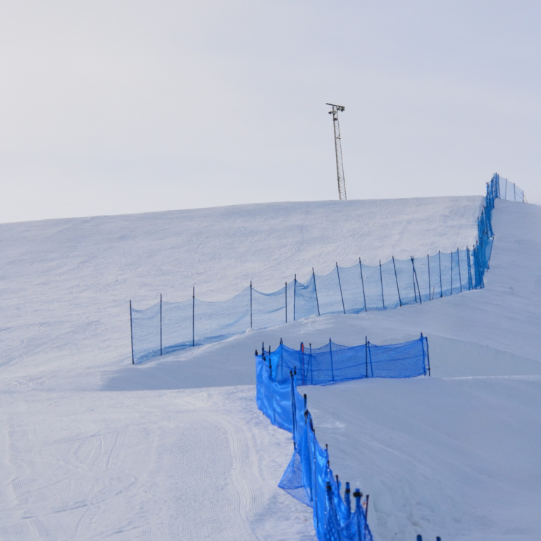 Snötäckt skidbacke med skyddsnät